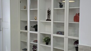 Una habitación con una estantería empotrada blanca que contiene varios objetos decorativos y algunas plantas en macetas.