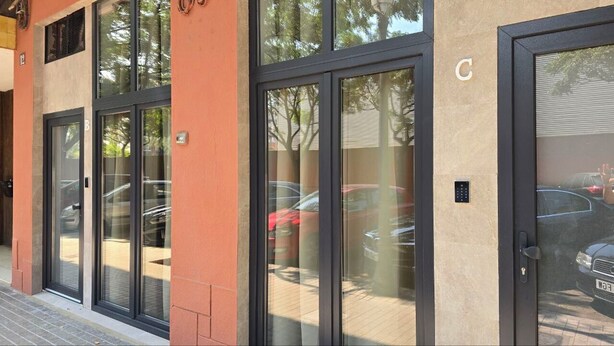 Entrada de un edificio con puertas de vidrio y un teclado electrónico.