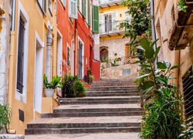 Una calle estrecha con una escalera de piedra que lleva a un edificio con balcón.