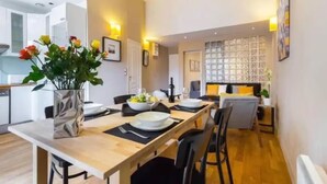 A modern dining area with a wooden table set for four, a vase of flowers, and a kitchen in the background. - Mediterranean Horizon (Villefranche-sur-Mer)