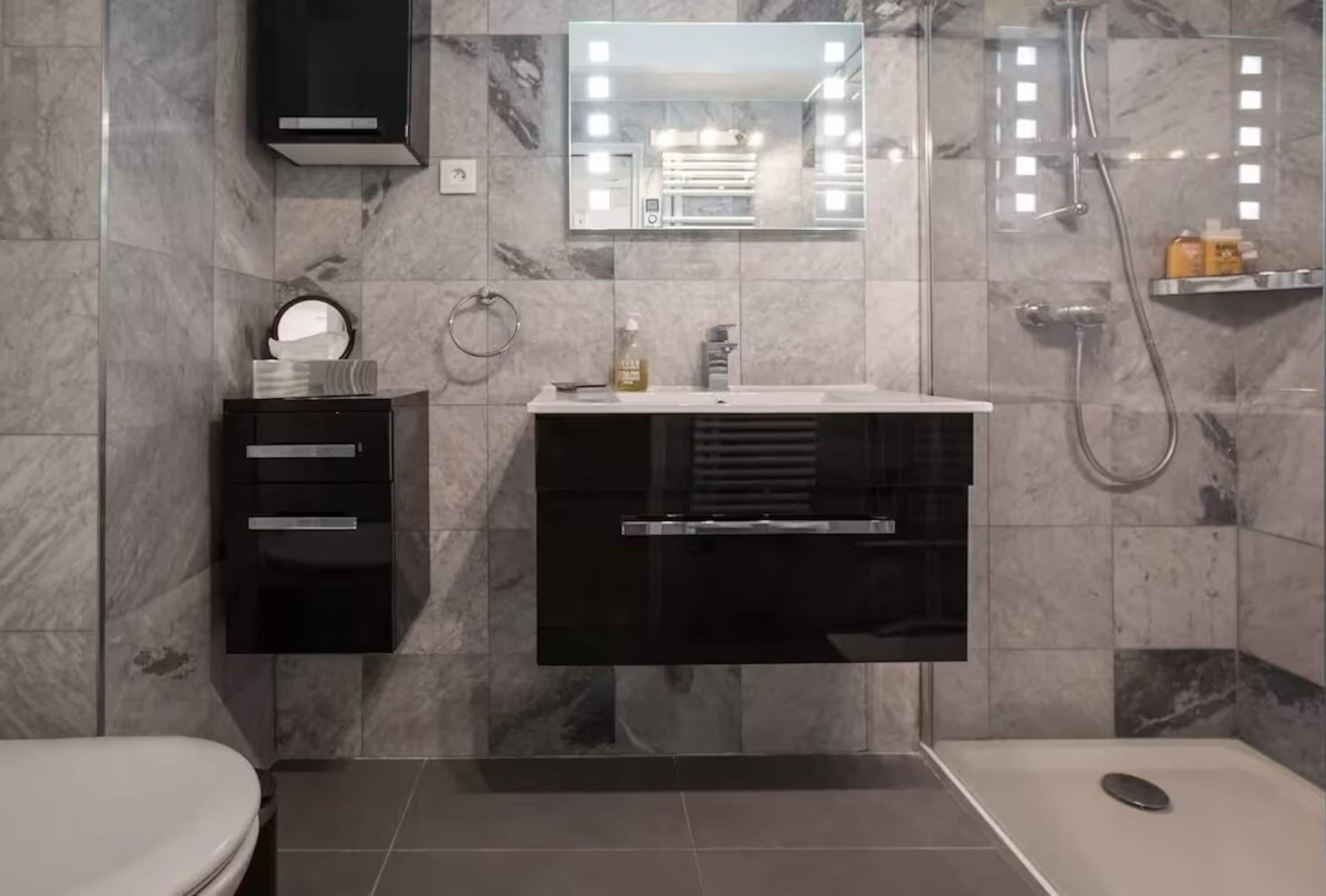 A modern bathroom with a vanity, mirror, and shower.