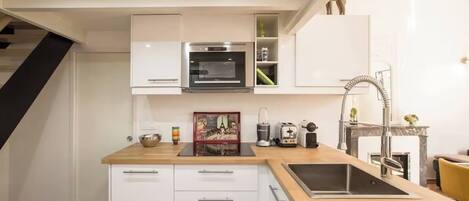 A modern kitchen with white cabinetry, a built-in oven, a sink, and a wooden countertop.