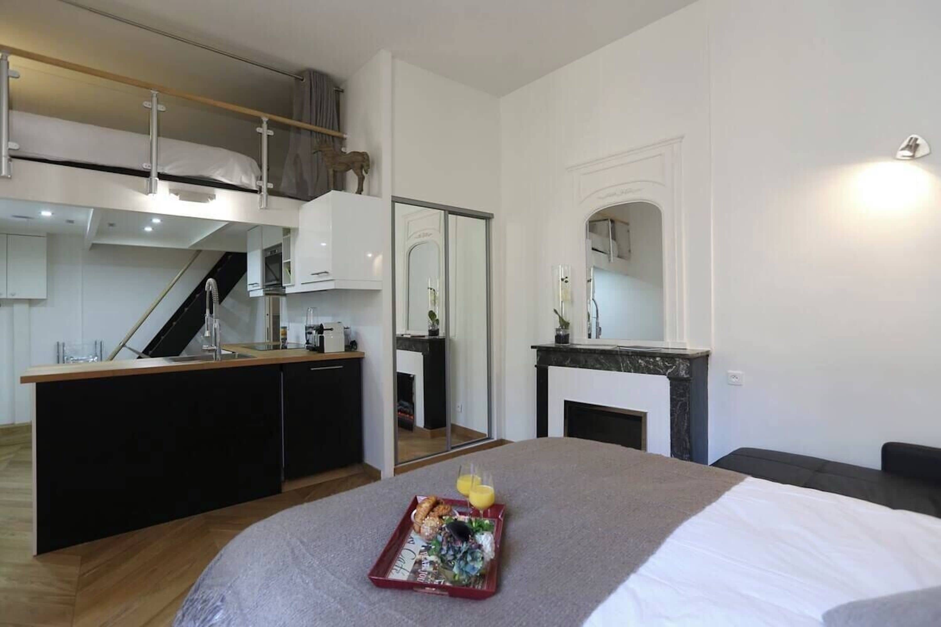 A modern bedroom with a bunk bed, a dining area, and a kitchen.