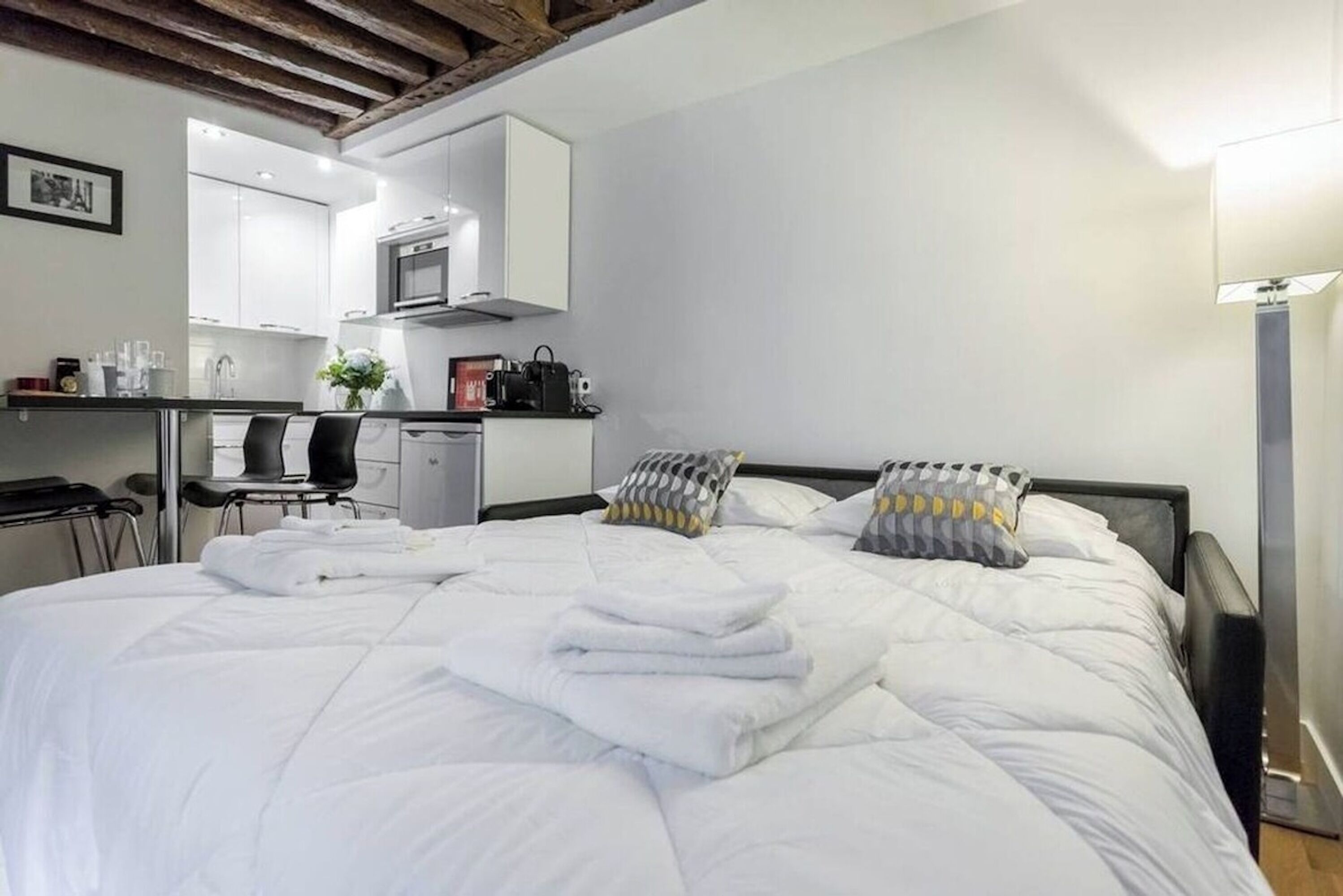 Una habitación de hotel con cama, escritorio, silla y kitchenette.