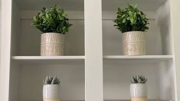 A white cabinet with two shelves, each holding a potted plant.
