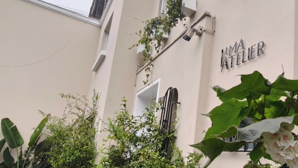 A building facade with a sign reading 'IMA ATELIER' and a window with a view of greenery. - Lima Atelier (Lima)