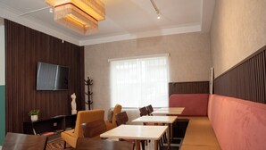 A modern hotel room with a flat-screen TV, a sofa, multiple tables, and a large window. - Lima Atelier (Lima)