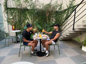 Two people seated at an outdoor table with a meal, surrounded by greenery and a staircase. - Lima Atelier (Lima)