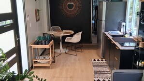 Eine kompakte Küche mit Essbereich, einem Kühlschrank und einer kleinen Sitzecke mit einer Couch und einem runden Tisch.