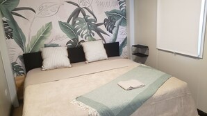 Ein ordentlich bezogenes Bett mit einem gemusterten Bettdeckenüberwurf und einer Tagesdecke, flankiert von zwei Kissen und einem schwarzen Kopfteil.