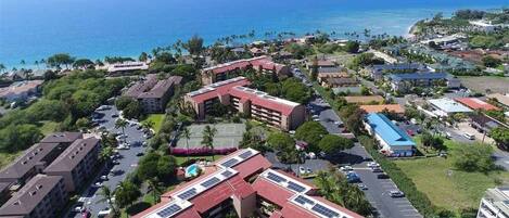 An aerial view of a coastal resort area with multiple buildings, parking lots, and a view of the ocean.