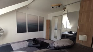 Et soveværelse med seng, spejl og billedkunst på væggen.