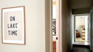 A hallway with a framed sign on the wall, a door leading to another room, and a tiled floor.
