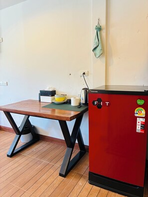 Une cuisine avec une table en bois, un réfrigérateur rouge et une serviette verte accrochée au mur.