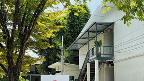 Der Eingang eines Mehrfamilienhauses mit Schild, einer Treppe und zwei draußen abgestellten Motorrädern.