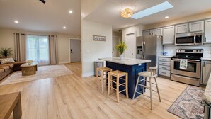 A modern kitchen with a central island, stainless steel appliances, and a dining area with a sofa and coffee table.