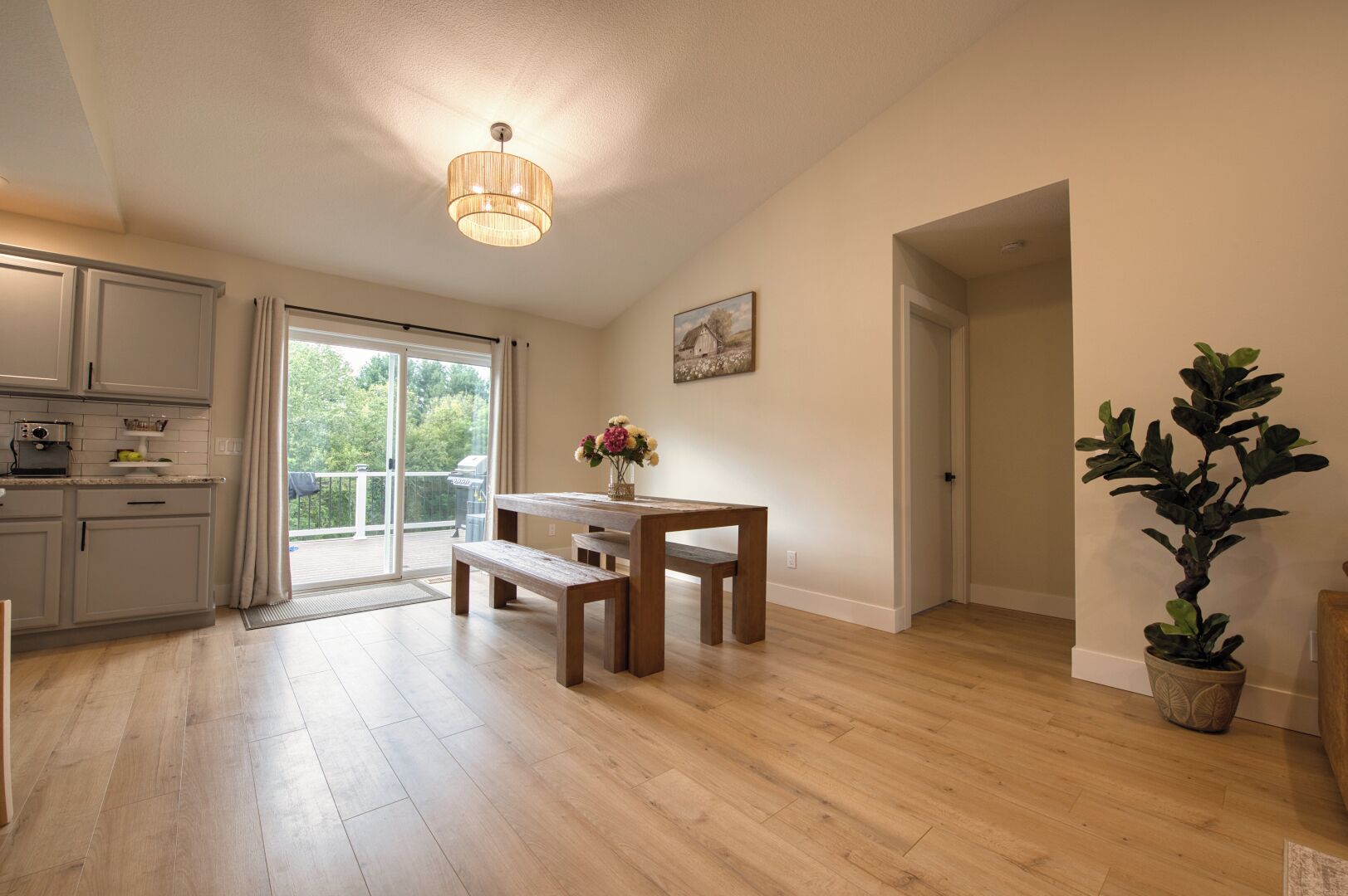 Eine geräumige Küche mit einer Schiebetür zum Balkon, einem Holzesstisch mit Bänken und einem Blumentopf.