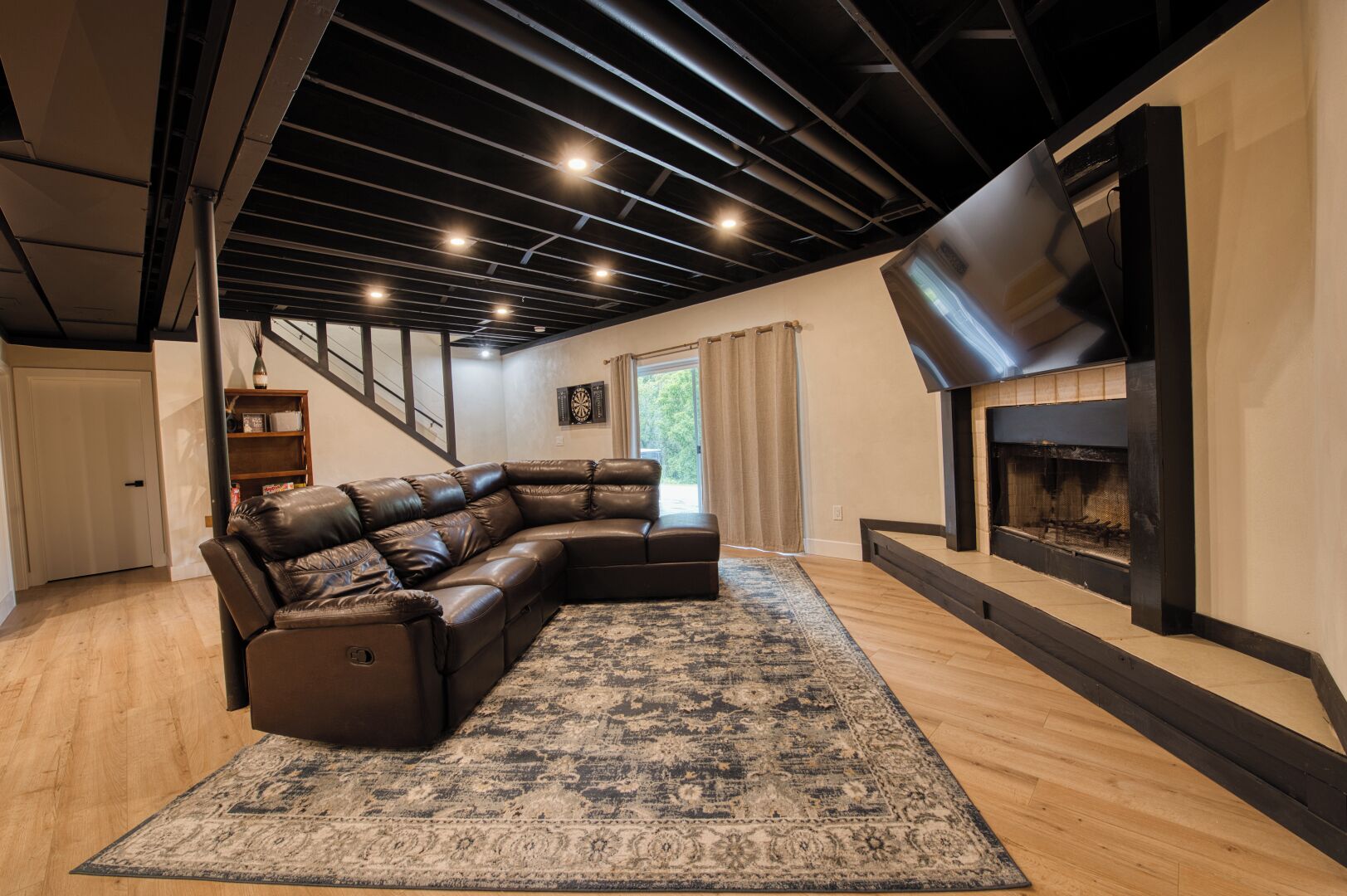 A modern living room with a leather sectional sofa, a fireplace, and a large rug.