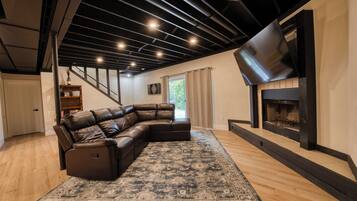 A modern living room with a leather sectional sofa, a fireplace, and a large rug.