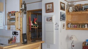 Een keuken met houten kastjes, een koelkast, een koffieapparaat en een kleine tafel met een lamp.