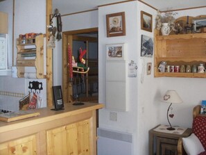 Eine Küche mit Holzschränken, einem Kühlschrank, einer Kaffeemaschine und einem kleinen Tisch mit einer Lampe.