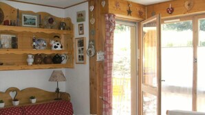 Een gezellige kamer met houten inrichting, een rode sofa met patroon, een tafel en een raam met gordijn.