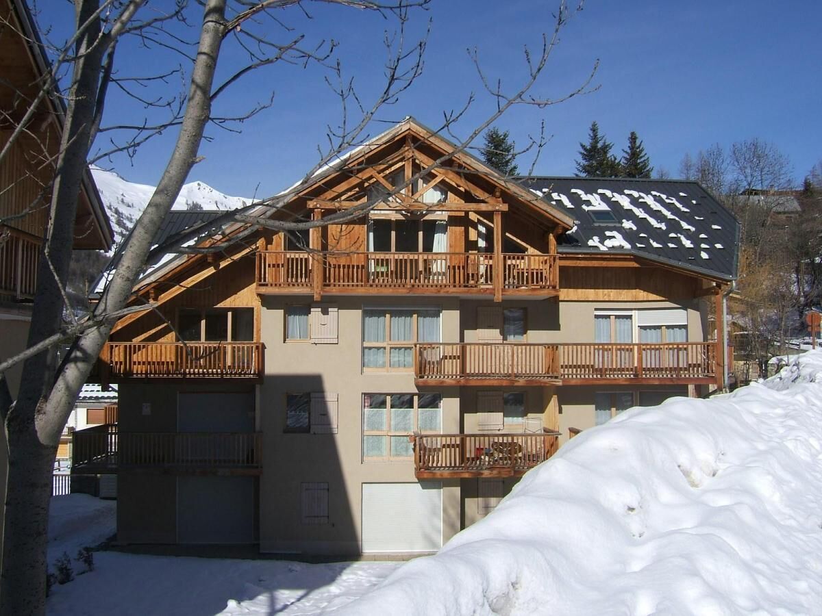 Un immeuble en bois à plusieurs étages, doté de balcons, et entouré de neige.