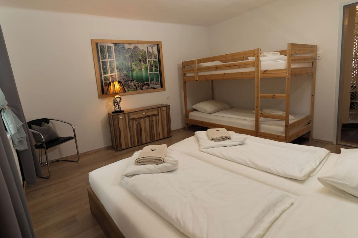 Quarto com duas beliches, um armário de madeira, uma cadeira e um quadro na parede.