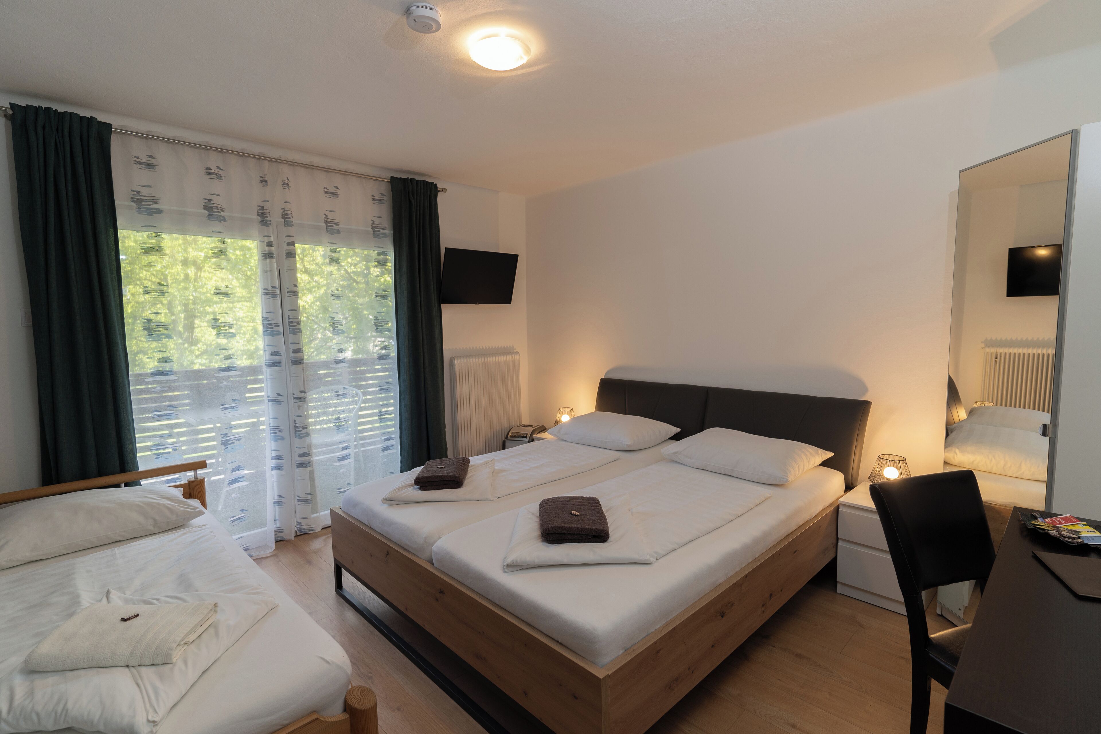 A modern hotel room with a wooden bed, a desk, and a chair.