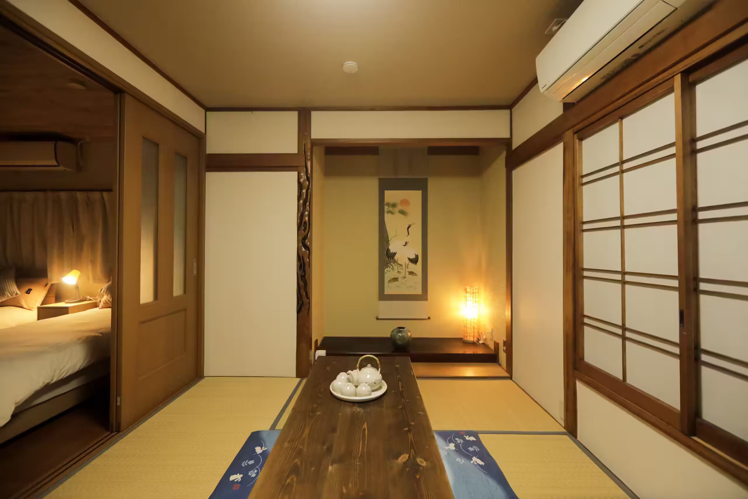 A traditional Japanese room with tatami flooring, a wooden table with a tea set, and sliding doors.