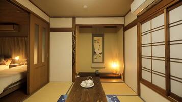 A traditional Japanese room with tatami flooring, a wooden table with a tea set, and sliding doors.