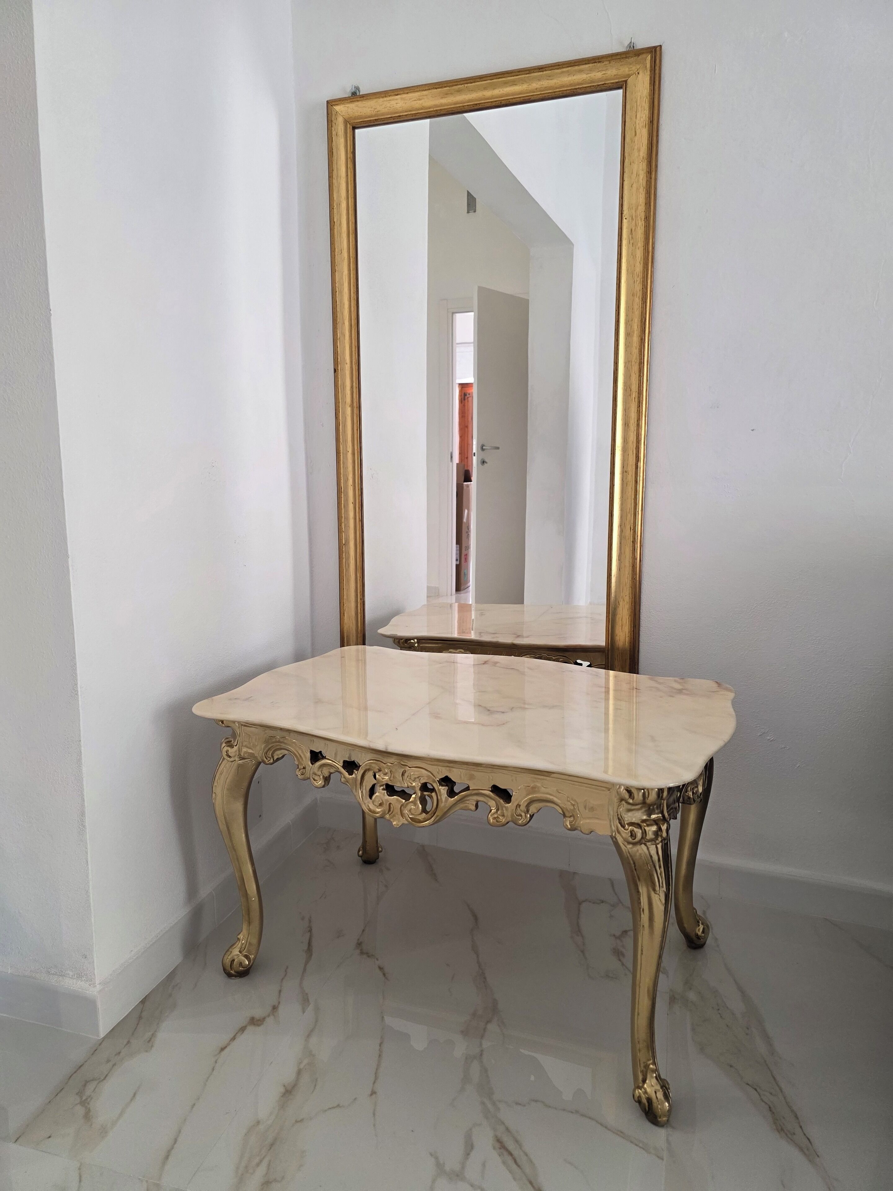 A corner room with a marble-topped table and a gold-framed mirror.