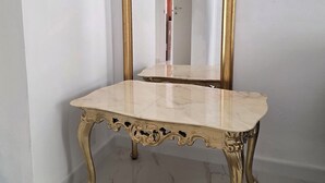 A corner room with a marble-topped table and a gold-framed mirror.