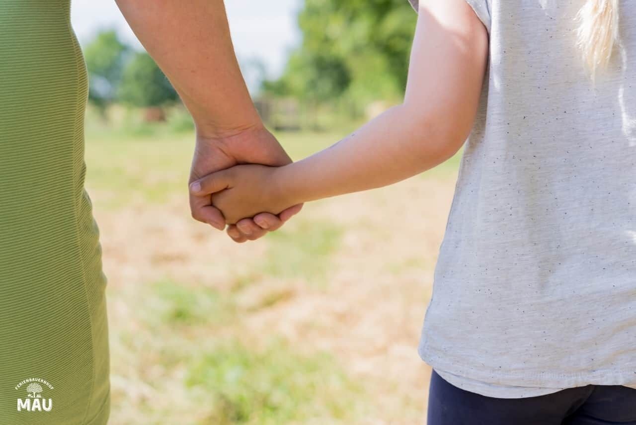 A close-up of two people holding hands in an outdoor setting.