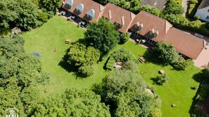 A row of terraced houses with a central lawn and surrounding trees. - Holiday Farm Mau - House 1 (Fehmarn)