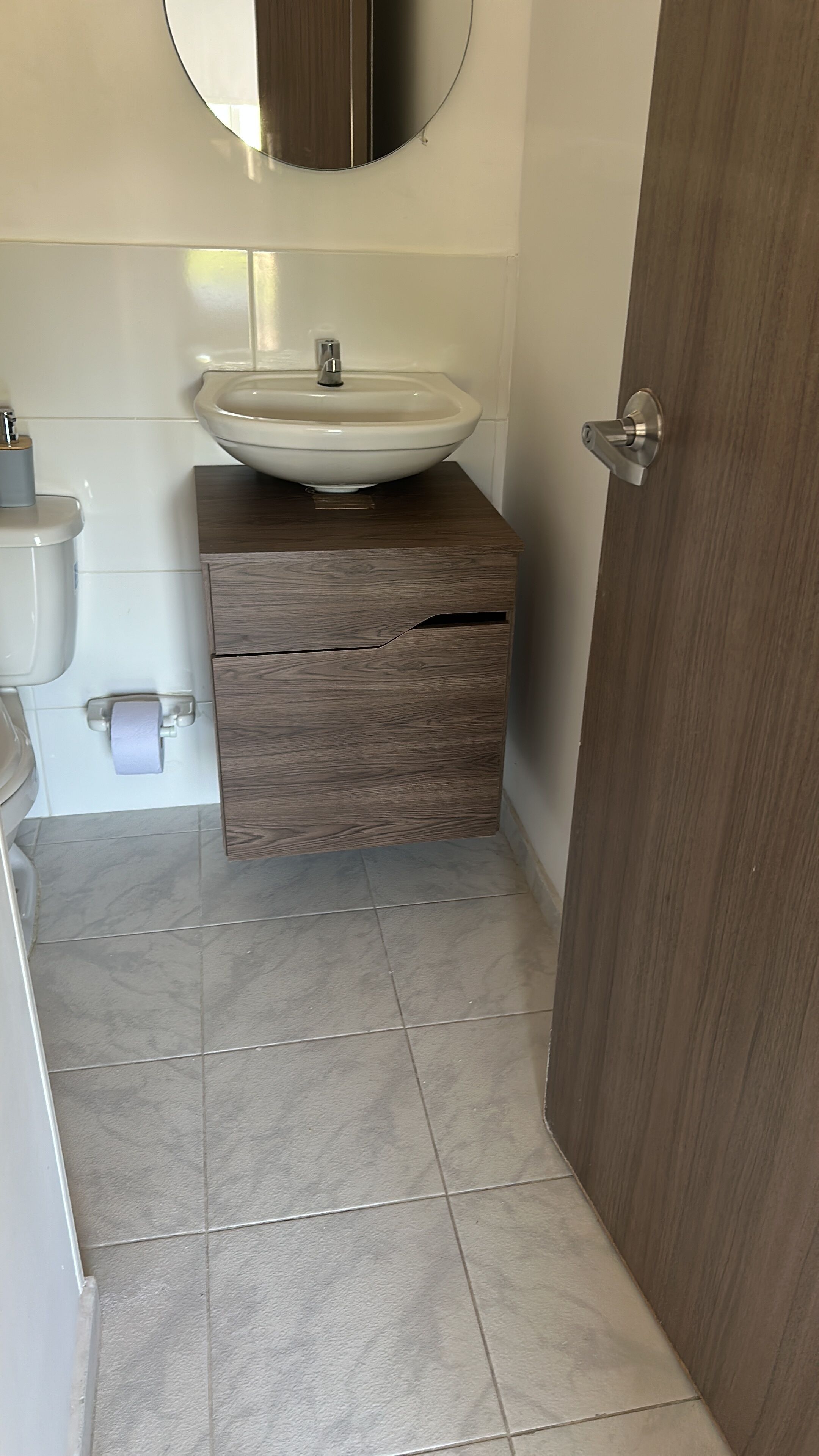 Ein Badezimmer mit weißem Waschbecken, Holz-Waschtisch und Toilette.