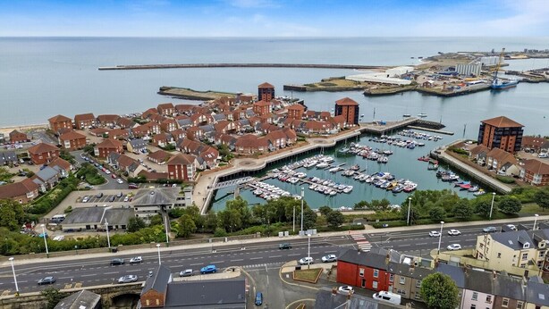 A coastal town with a marina, residential buildings, and industrial facilities.