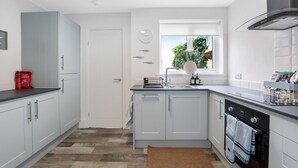 A modern kitchen with light grey cabinets, a black countertop, and a built-in oven.