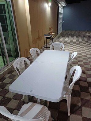 A white table with six chairs in an outdoor area with a checkered floor.