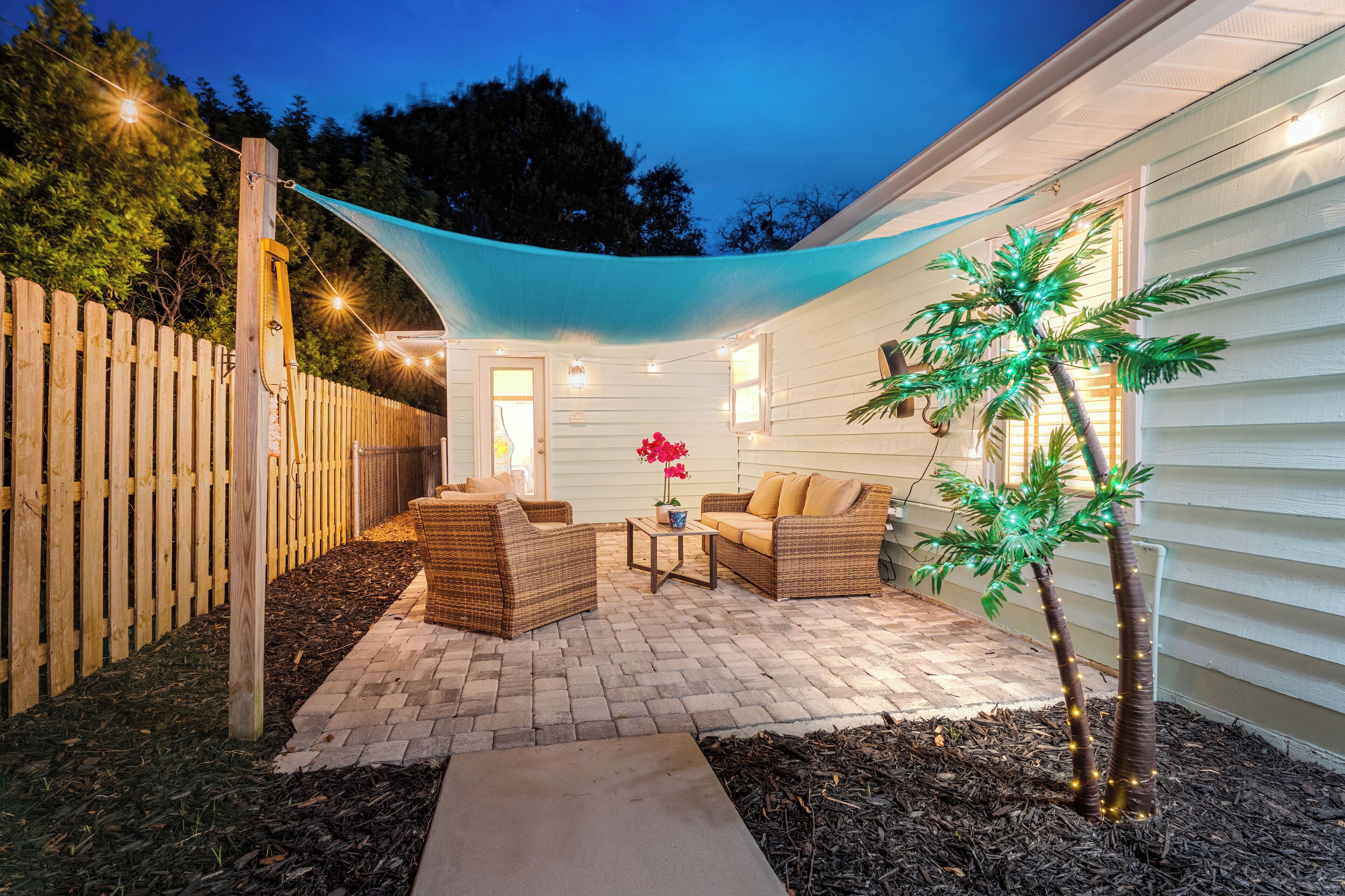 A patio with wicker furniture, a small table, and a potted plant.