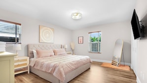 Une chambre à coucher avec un lit, des tables de chevet, une télévision et une fenêtre.
