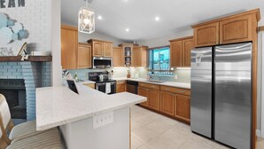 Une cuisine moderne avec des meubles en bois, des appareils électroménagers en acier inoxydable et un plan de travail blanc.
