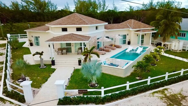 Une maison à deux étages avec une piscine, un patio couvert et une clôture blanche.