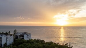 Een kustgezicht met moderne gebouwen en een zonsondergang boven de zee.