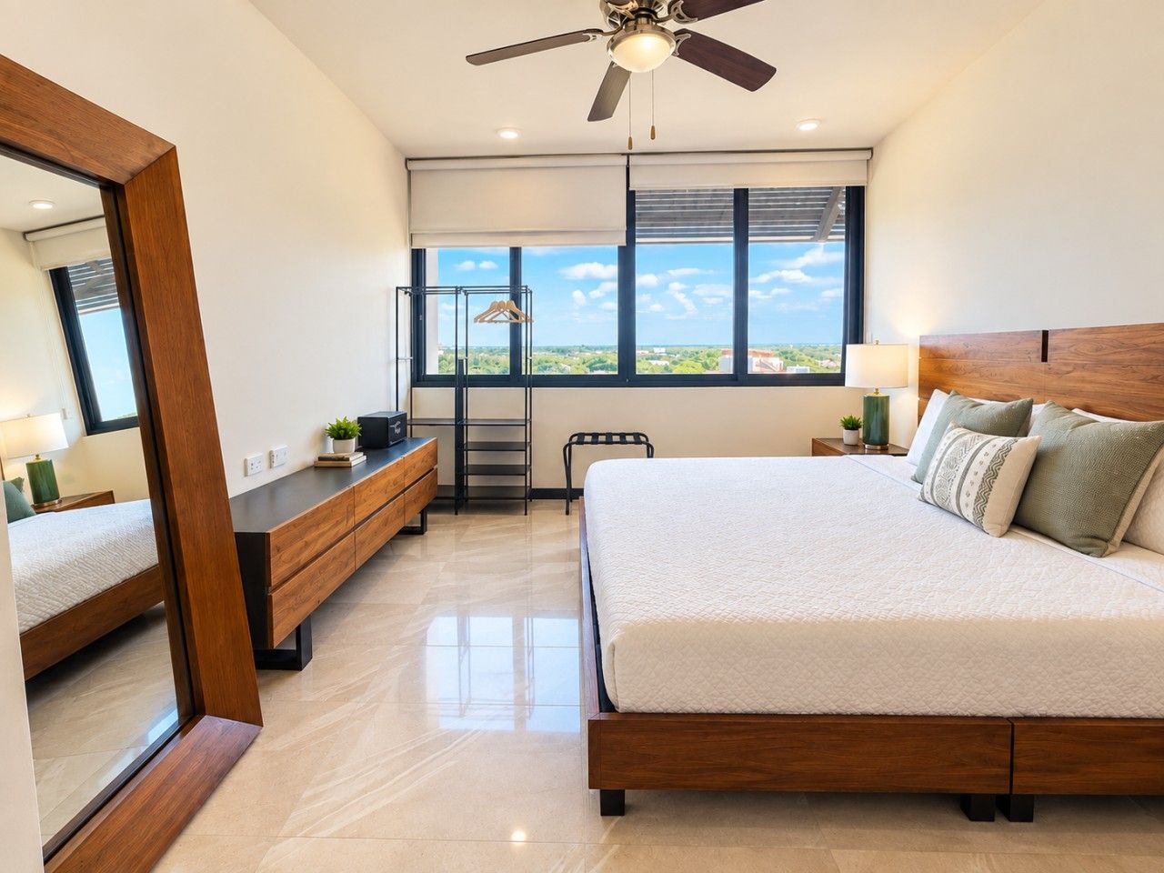 A modern bedroom with a large bed, a ceiling fan, a view through the window, and a wooden dresser.