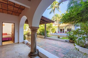 Ein Innenhof mit Pool, überdachter Sitzbereich und einem Zimmer mit Bett und Tür.