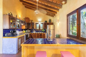Una cocina con una isla de azulejos azules, armarios de madera y un ventanal grande.
