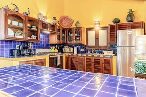A kitchen with blue tiles, wooden cabinets, and various kitchen appliances.