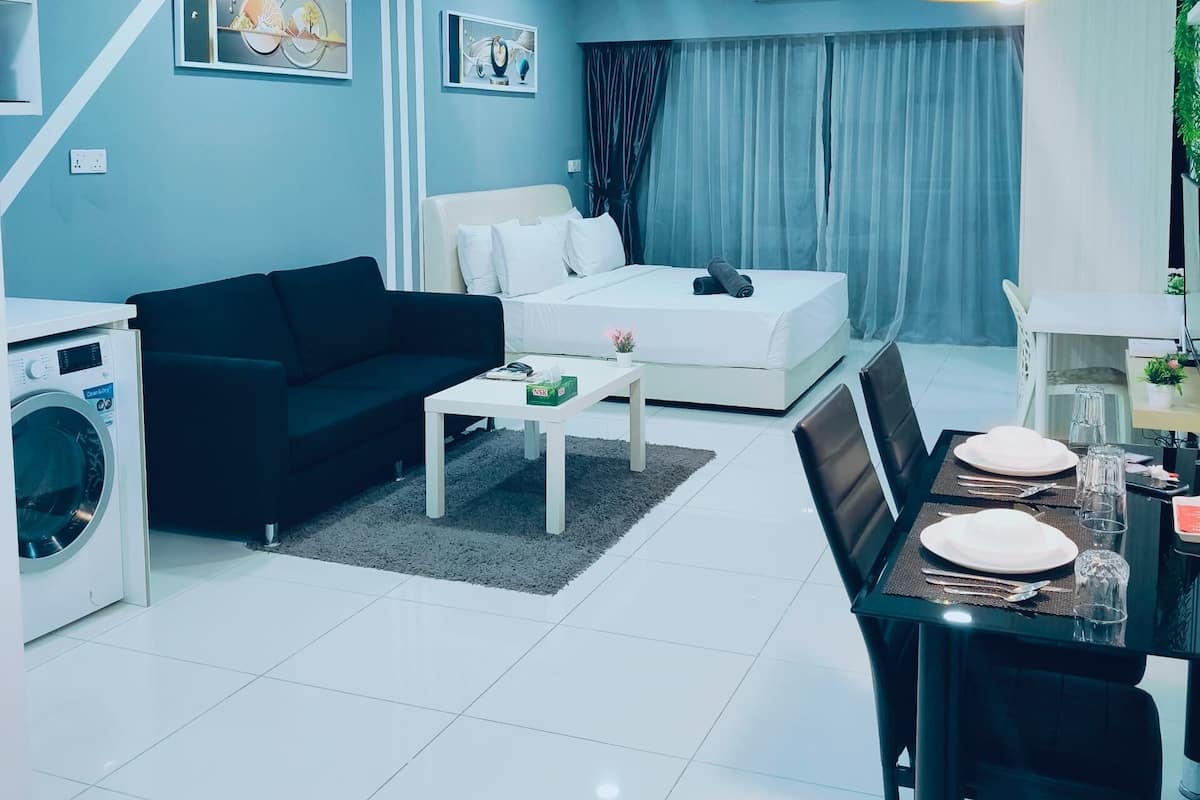 Un salon moderne avec un canapé, une table à manger dressée pour deux personnes et un lave-linge.