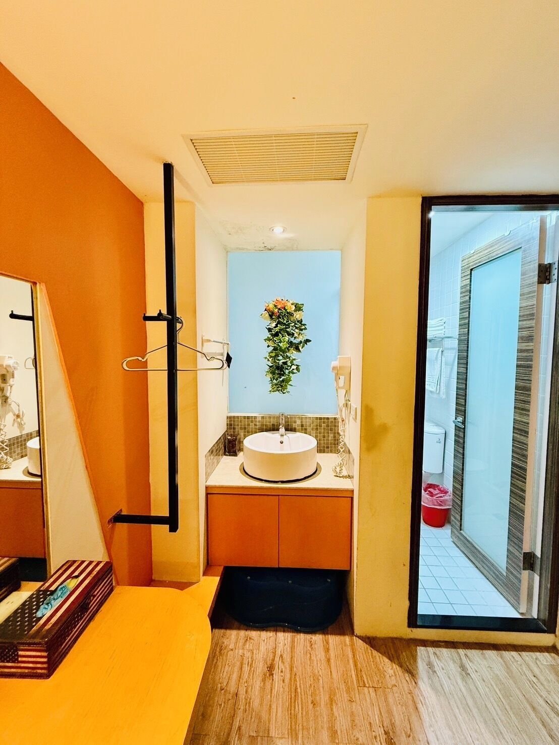 A modern bathroom with a round sink, a mirror, and a decorative plant.